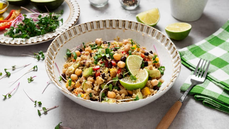 Ein Teller Quinoa-Salat mit Kichererbsen und Limette steht auf einem Tisch