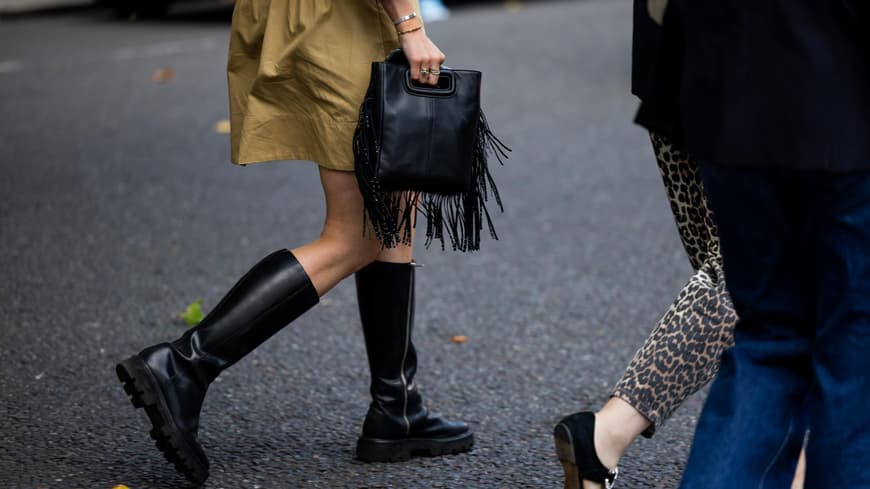 Frau mit schwarzem Stiefel und Fransen-Handtasche