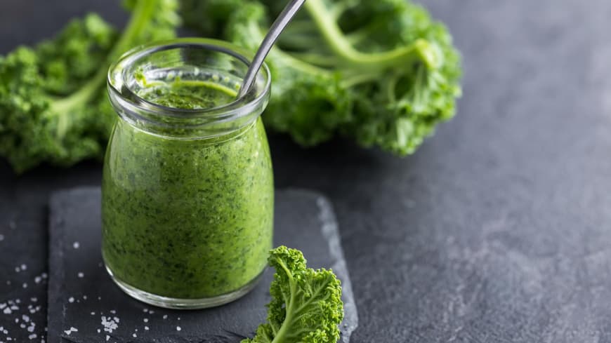 Grünkohl-Pesto im Glas auf einem grauen Tisch