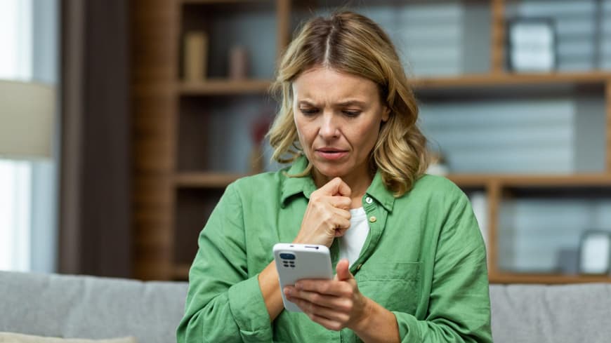 Frau schaut verwundert auf ihr Smartphone