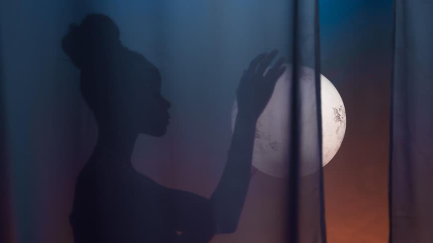 Frau mit Dutt hält den Vollmond in der Hand