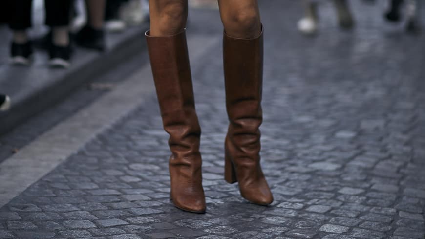Frau trägt schwarzes Kleid und braune Stiefel
