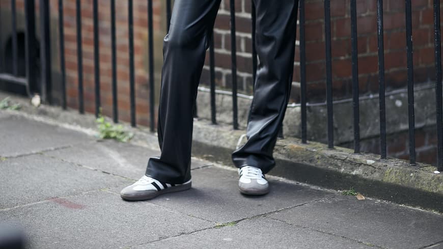 Frau trägt auf London Fashion Week weiße Retro-Sneaker und Lederhose
