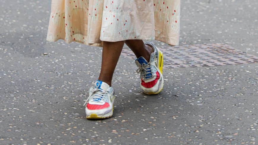 Frau trägt bunte Sneaker und ein Midikleid auf London Fashion Week