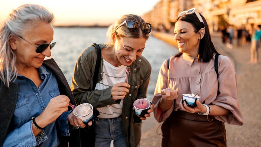 Drei Frauen lachen essen ein Eis im Becher