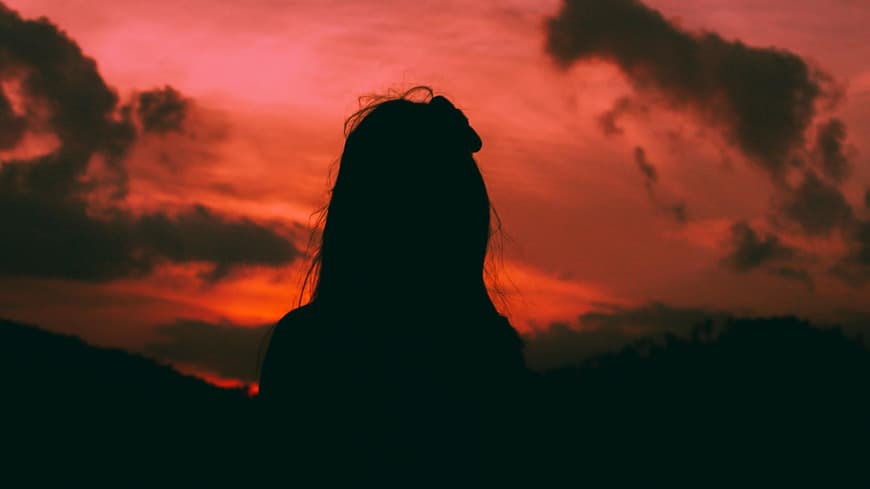 Silhouette einer Frau vor einem roten Himmel
