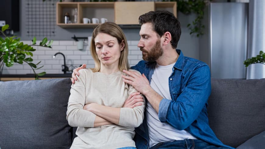 Paar sitzt auf dem Sofa, der Mann umarmt die Frau