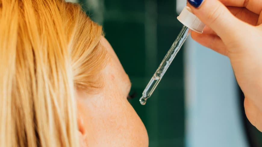 Frau trägt Serum auf ihr Gesicht auf