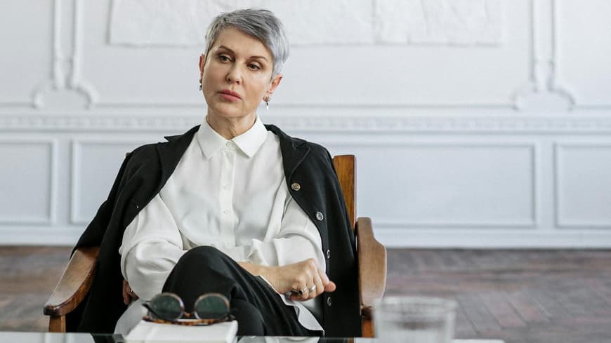 Frau sitzt im Sessel vor einem Couchtisch.