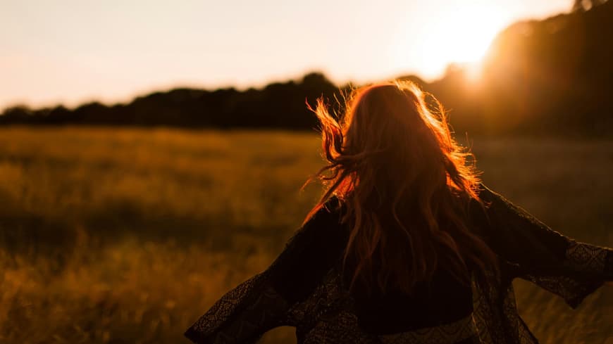 Frau auf einem Feld beim Sonnenuntergang