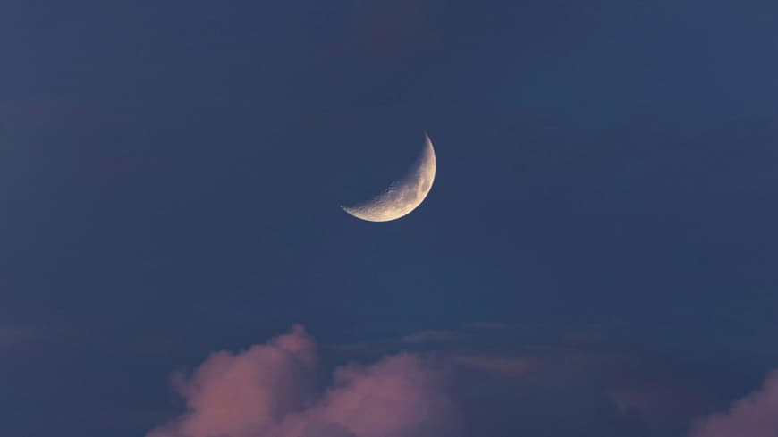 Halbmond am Himmel über den Wolken