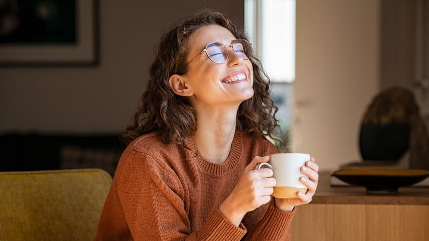 Frau mit Tasse in der Hand lacht
