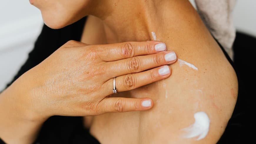 Frau cremt sich mit Bodylotion ein