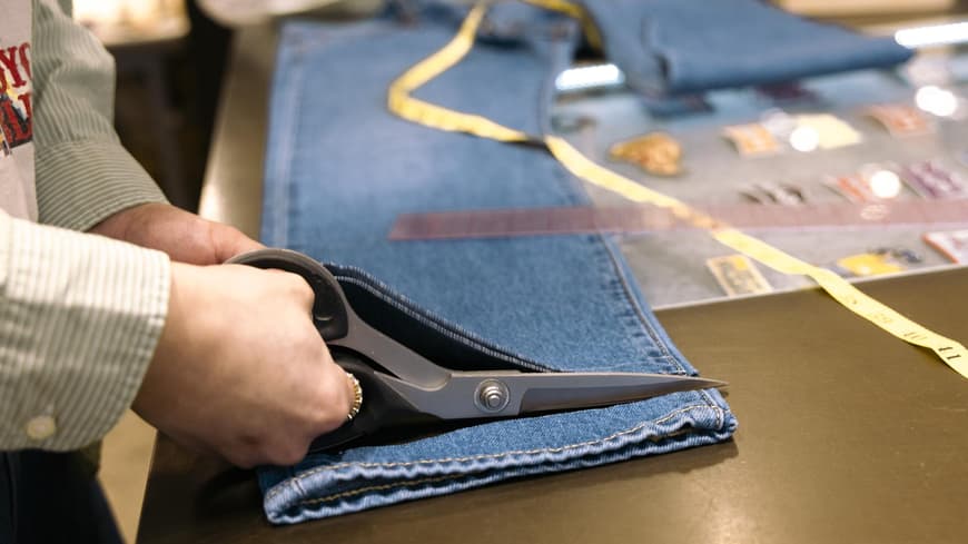 Person kürzt eine Jeans