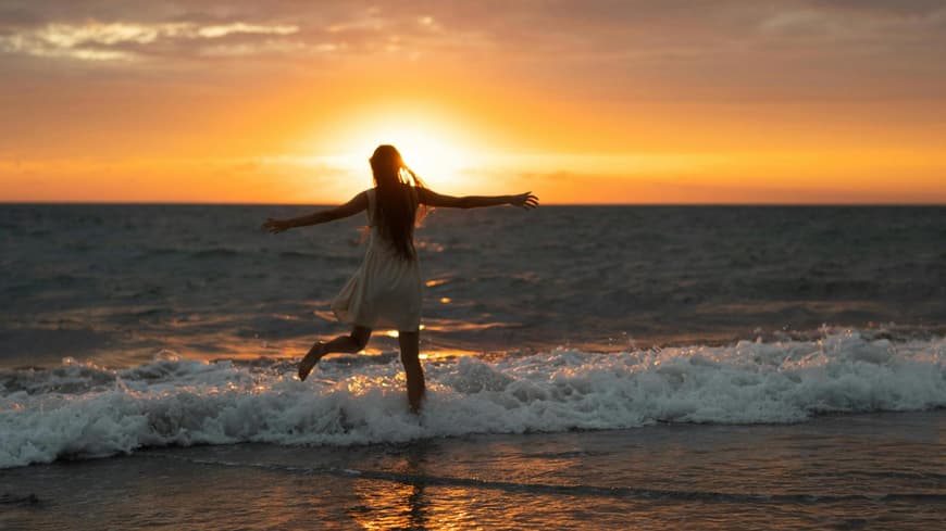 Frau im Meer beim Sonnenuntergang