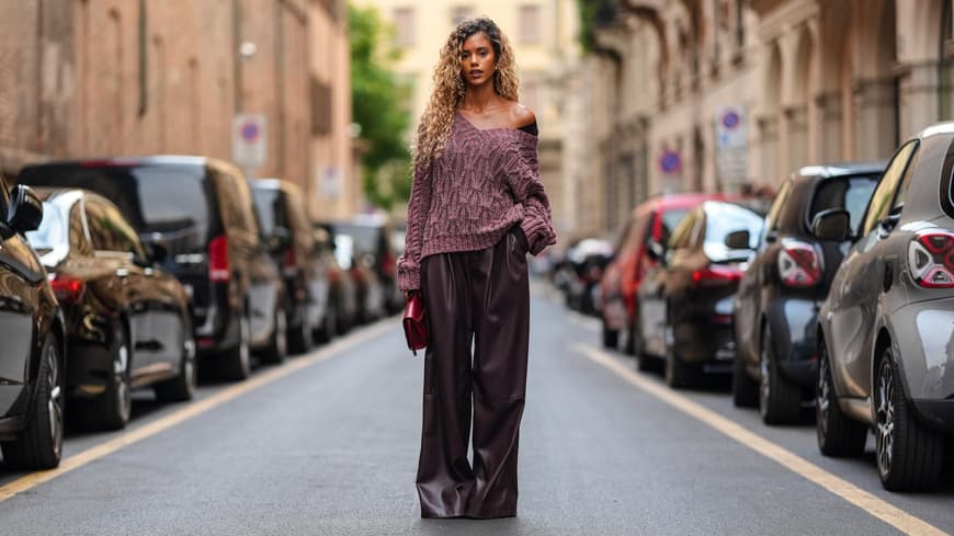 Eine Frau trägt einen dunkelroten Strickpullover mit einer Lederhose.