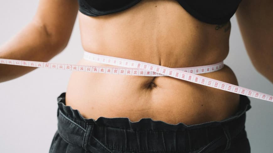 Maßband um den Bauch einer Frau