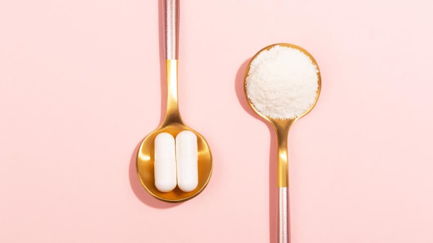 Kapseln und Pulver auf goldenen Löffeln.