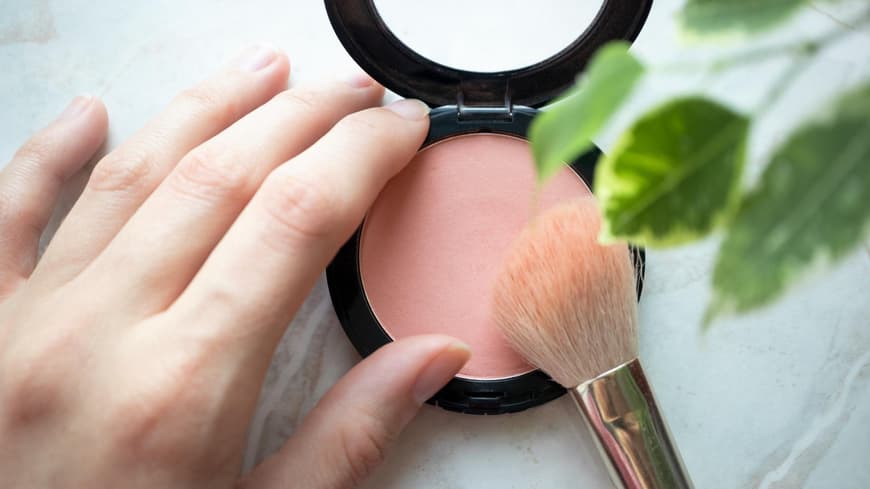 Blush in Puderform mit einem Pinsel.