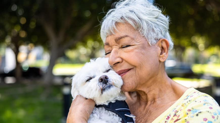 Frau schmust mit einem weißen kleinen Hund.