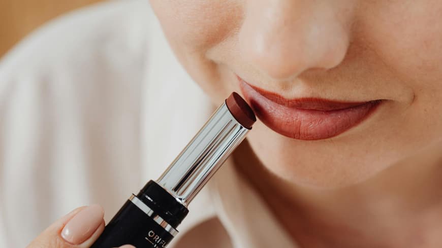 Frau schminkt sich mit Lippenstift.