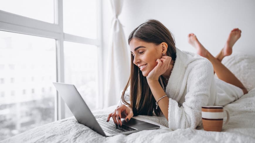 Frau auf dem Bett am Laptop