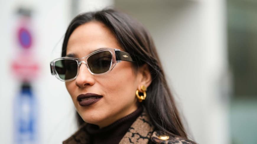 Frau trägt kastanienbraunen Lippenstift und eine Sonnenbrille.