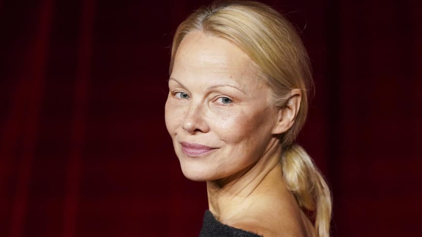 Pamela Anderson guckt über die Schulter nach hinten.