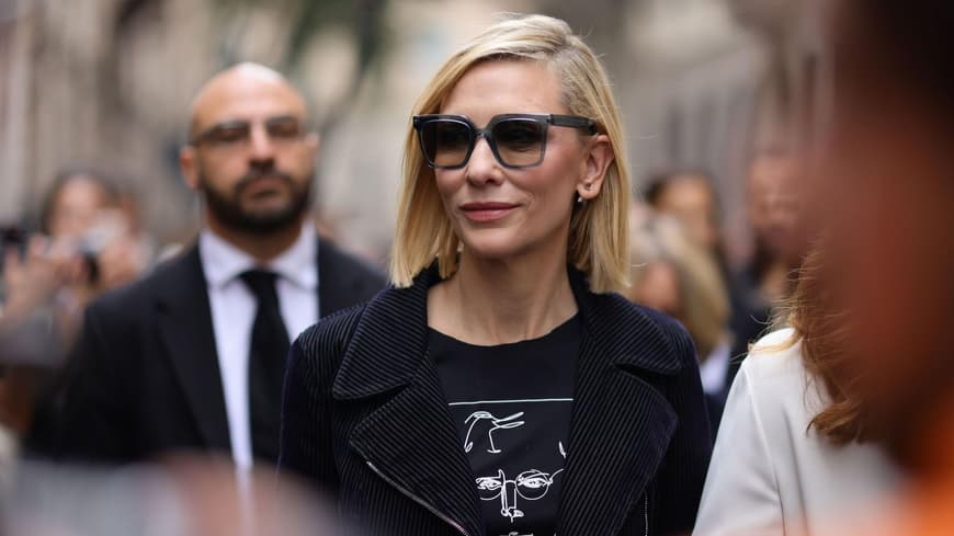 Frau mit blonden kurzen Haaren, seitlichem Scheitel und Sonnenbrille.