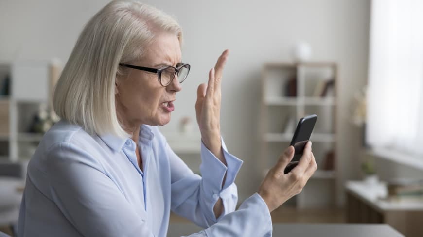 Frau liest etwas auf dem Handy und beschwert sich.