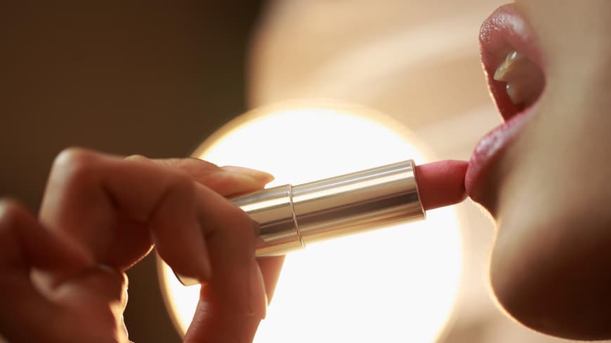 Frau trägt Lippenstift auf die Lippen auf.