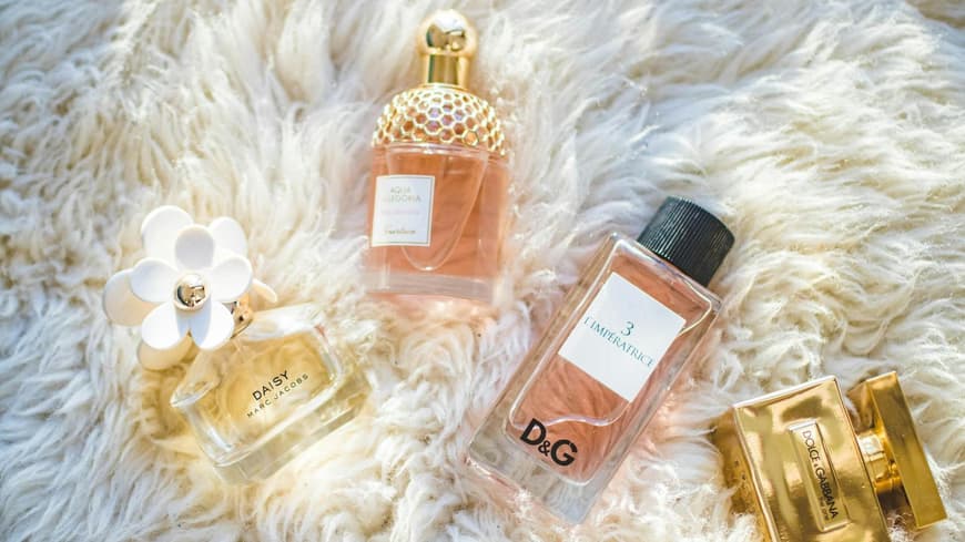 Verschiedene Parfums auf einem flauschigen weißen Teppich.