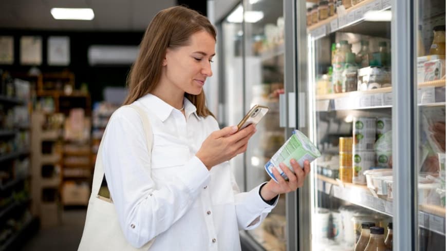 Eine Frau steht im Supermarkt vor einem Kühlregal
