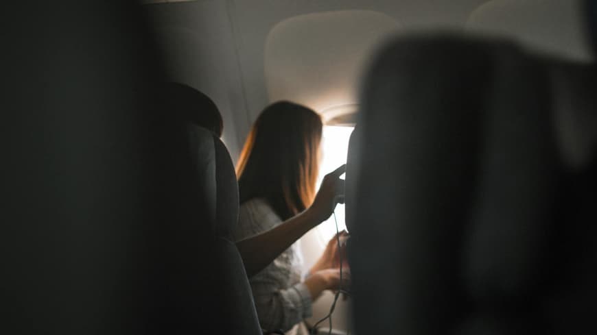 Frau sitzt im Flugzeug und guckt aus dem Fenster.