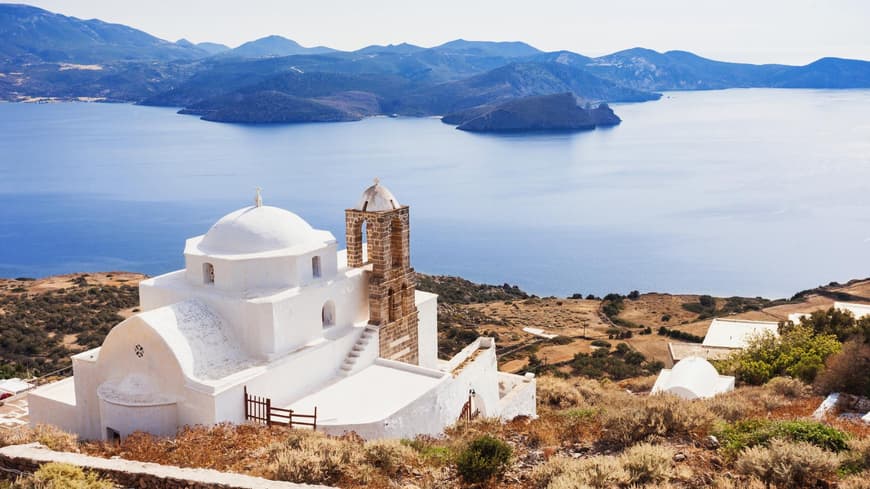 Eine griechische Kapelle mit dem Meer und Landschaft im Hintergrund.