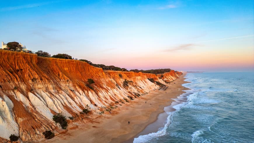 Rötliche Klippen und blaues Meer an der Praia da Falésia in Portugal.