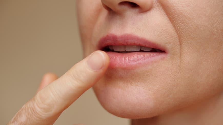Frau cremt Lippen ein