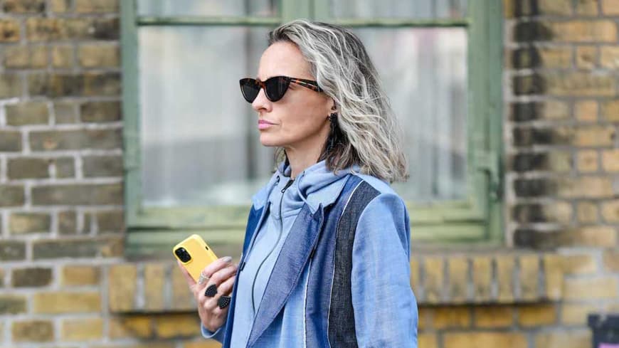 Ältere Frauen mit grauen Haaren, Sonnenbrille und einem Jeansmantel.