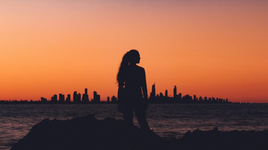 Frau steht vor Abendhimmel