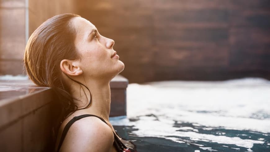 Frau von der Seite liegt im Pool und guckt in die Luft.