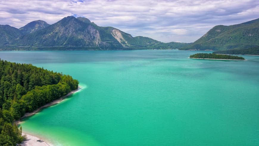 Ein riesiger, türkisfarbener See mit Gebirge im Hintergrund.
