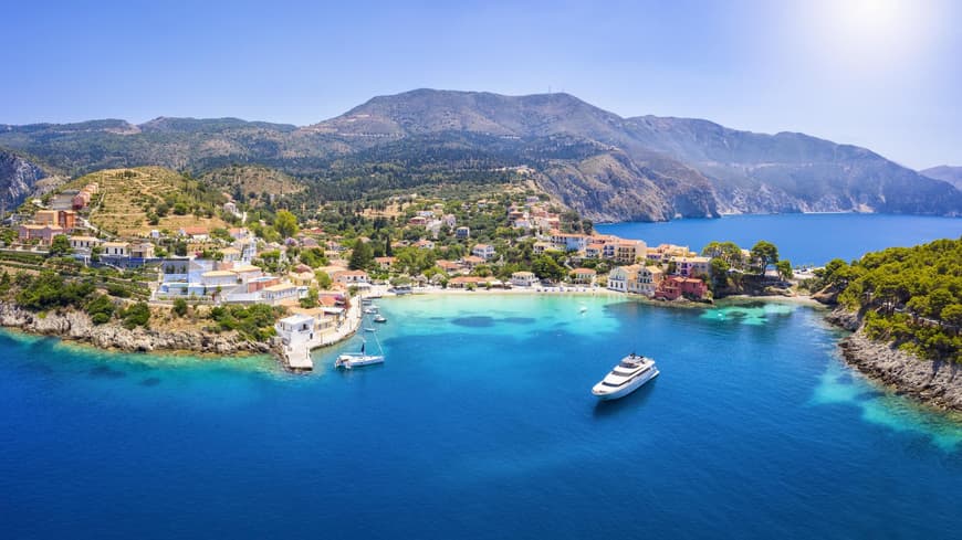 Luftaufnahme einer griechischen Insel mit Häusern auf dem Festland und Booten im Wasser.