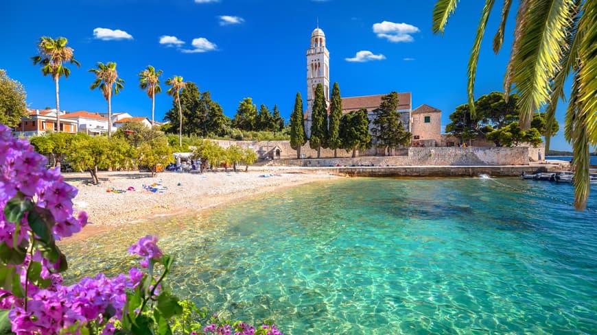 Strand mit ein paar Handtüchern, Palmen und einer Kirche im Hintergrund