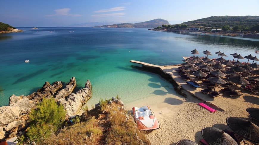 Ein Blick auf den Strand und das Meer von Ksamil mit Sonnenschirmen und Liegen.