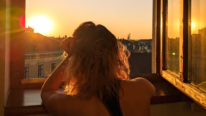 Frau sitzt am offenen Fenster