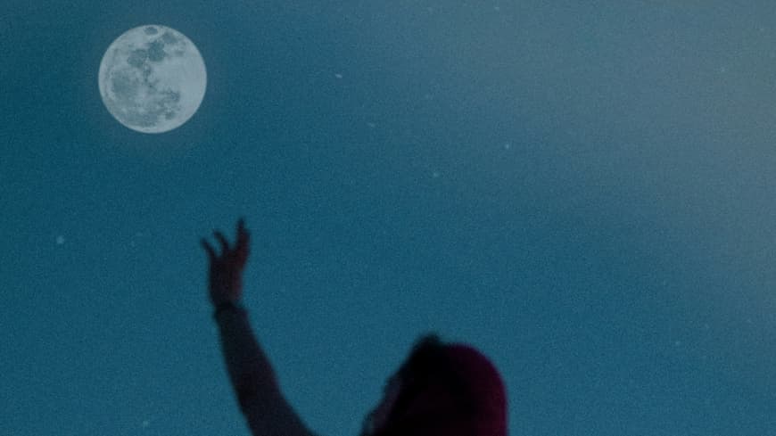 Frau streckt Arm zum Mond