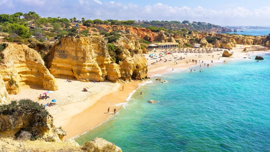 Ein Strand mit Urlaubern, türkisblauem Wasser und Klippen.