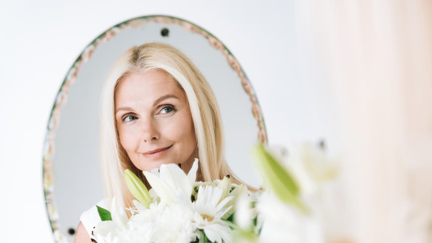 Blonde Frau schaut in den Spiegel