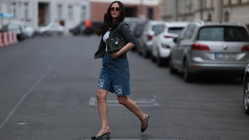 Frau mit dunklen Haaren und Sonnenbrille trägt Jeans-Shorts mit Slingback-Pumps.