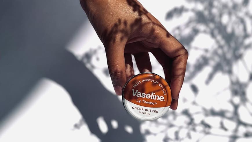 Frau hält eine kleine Dose mit Vaseline in der Hand.